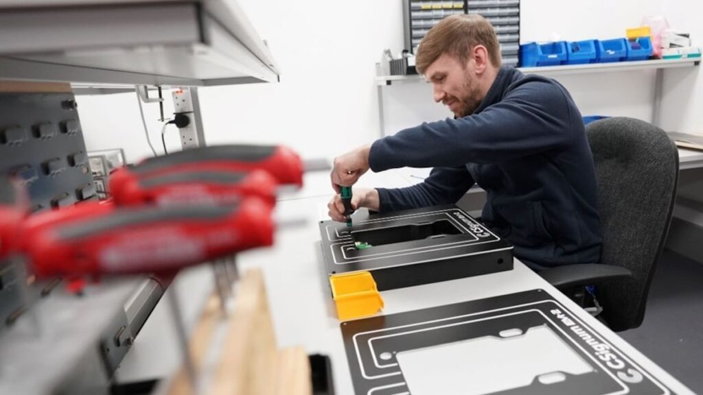 CSignum engineer Kyle Watson assembling monitoring equipment at a workbench