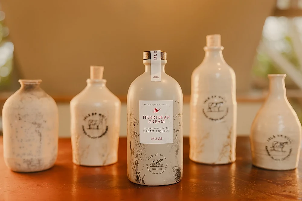 Hebridean Cream Liqueur in its ceramic bottle, surrounded by Isle of Mull Cheese pottery